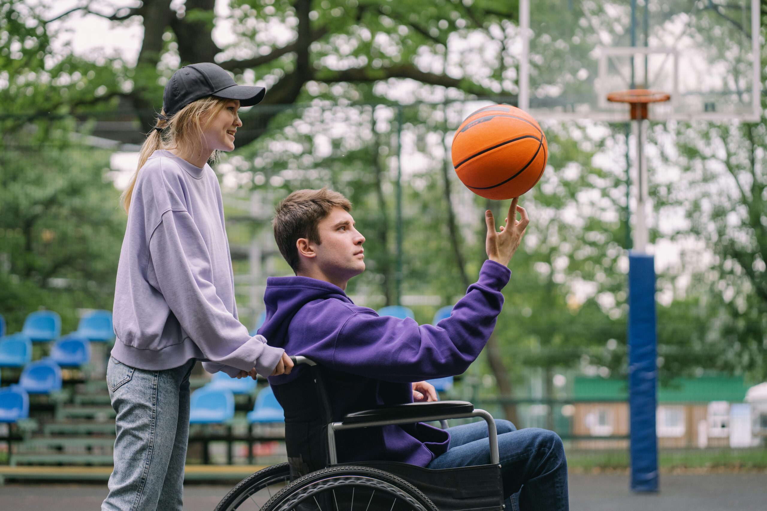 A wheelchair basketball player spinning a ball with a teammate nearby