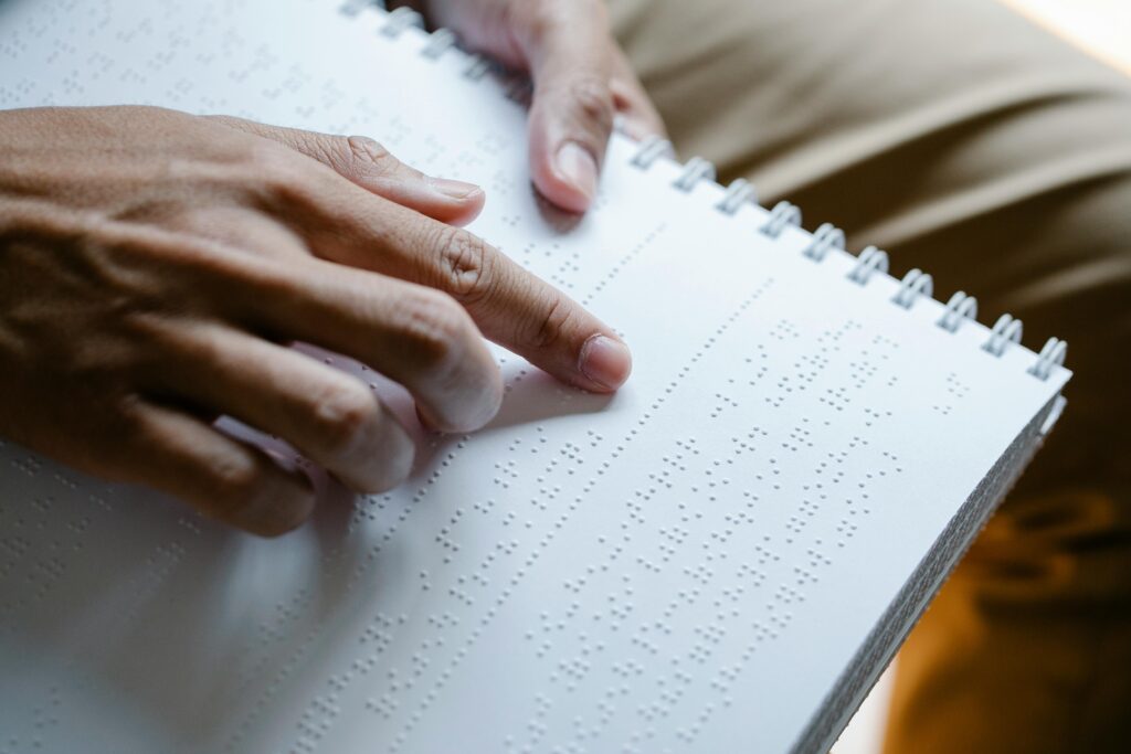 Hands reading an open book written in braille