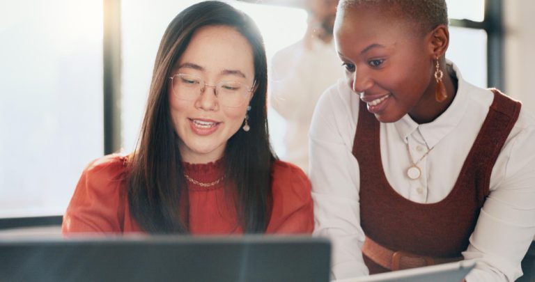 Two young women collaborating at a computer.