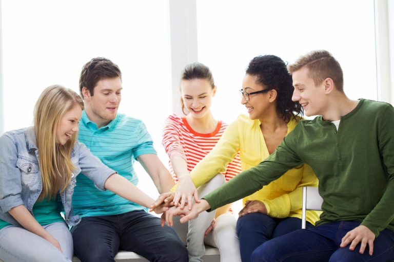 Young people placing their hands together during a group activity.