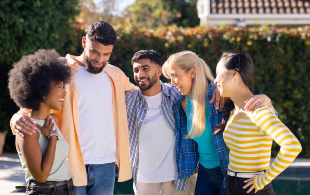 Five young adults standing together outdoors.