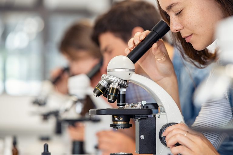 A student looking through a microscope in a laboratory.