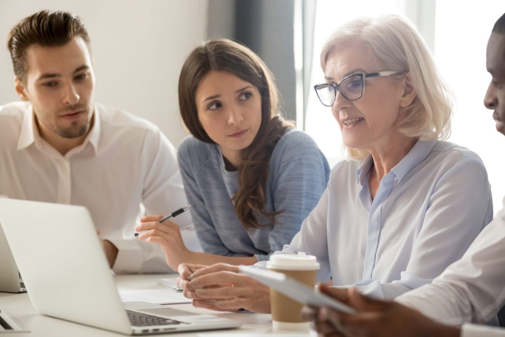 Young professionals learning from an experienced colleague during a workplace meeting.