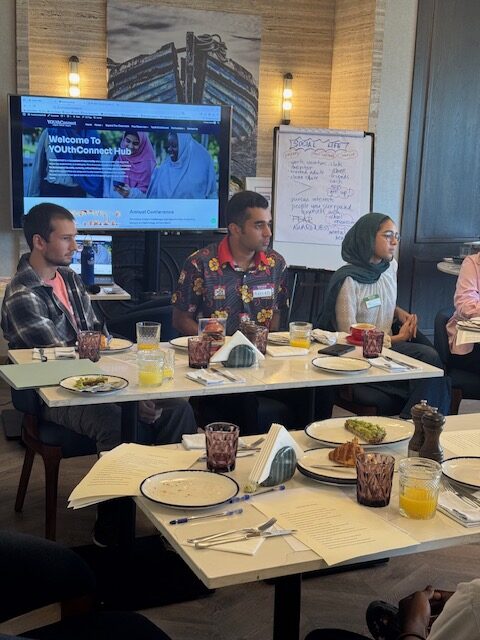 Participants listen to a speaker during a seated round-table session.