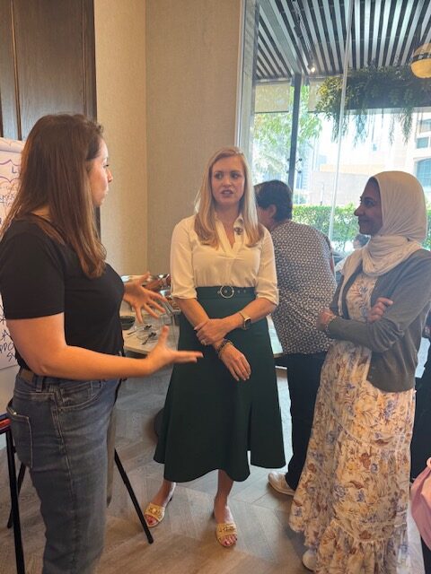 Mentors and participants talk through ideas beside the workshop wall.