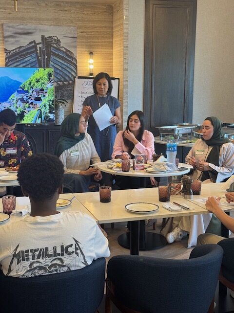A facilitator guides students through questions at the round table.